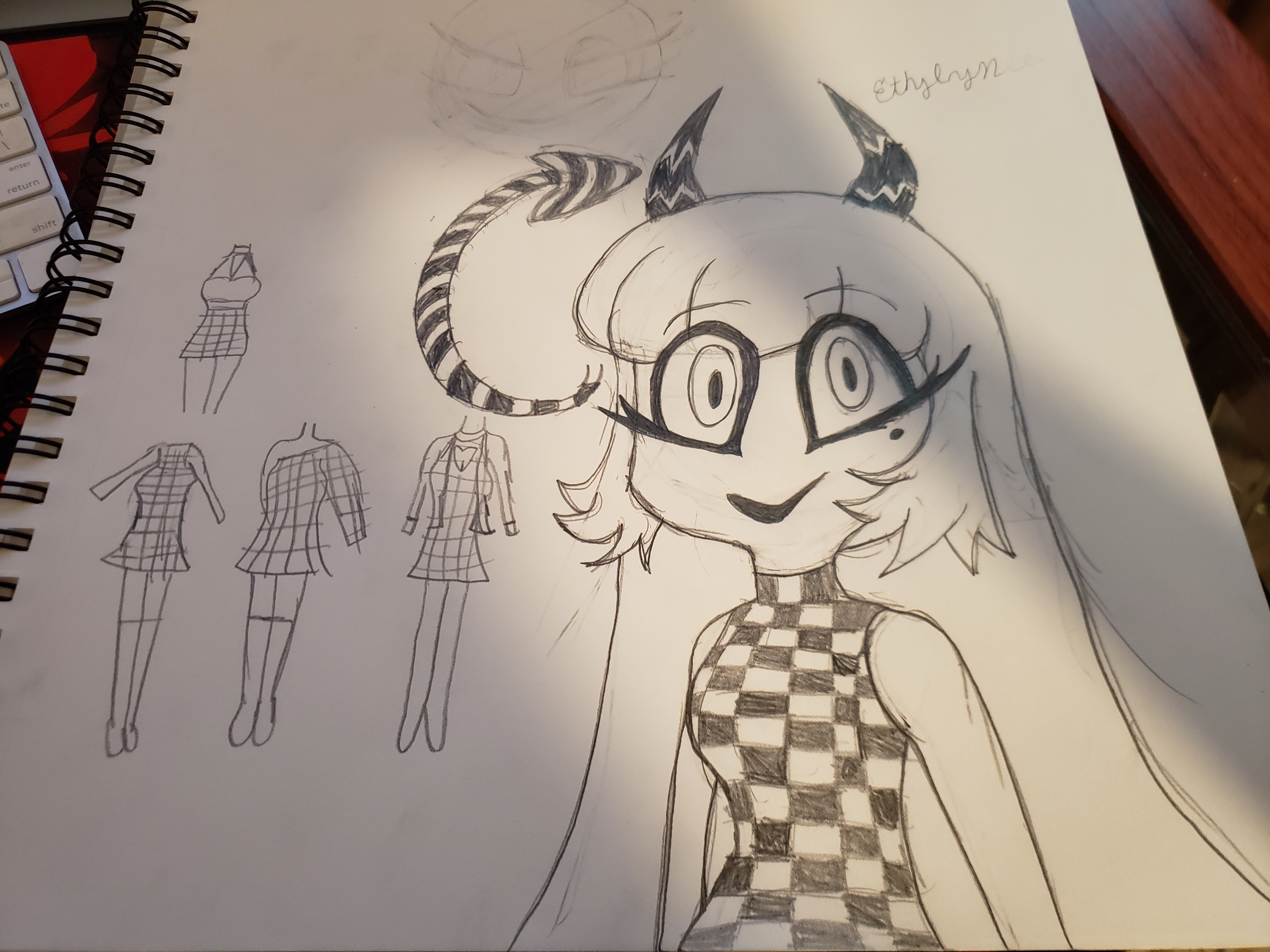 Photo of a sketchbook showing a half-body sketch of Ethylynn and her tail design. To the left are four different rough outfit designs.